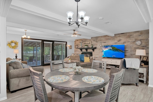 dining room featuring ceiling fan with notable chandelier, a brick fireplace, beam ceiling, and light hardwood / wood-style floors