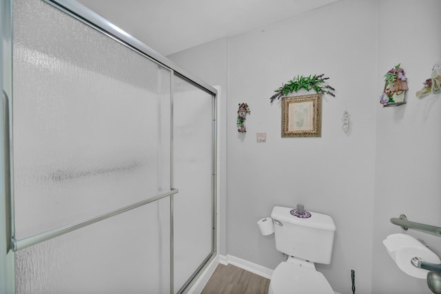 bathroom with hardwood / wood-style floors, toilet, and a shower with door