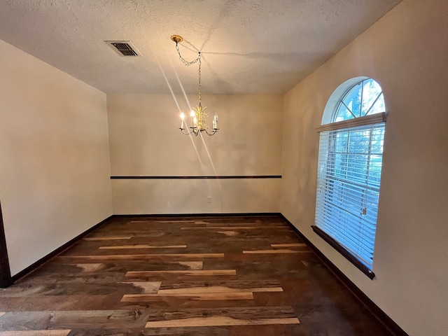 unfurnished dining area with dark hardwood / wood-style floors, a notable chandelier, and a textured ceiling