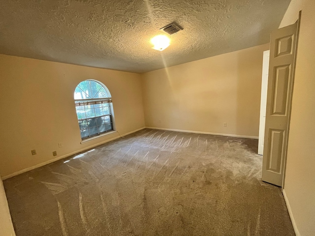 unfurnished room with carpet and a textured ceiling