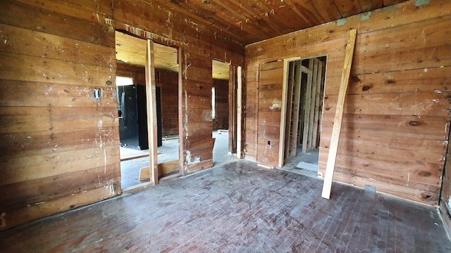 unfurnished room featuring wooden walls