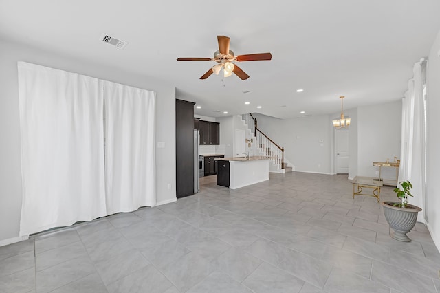 unfurnished living room with ceiling fan with notable chandelier and light tile patterned floors