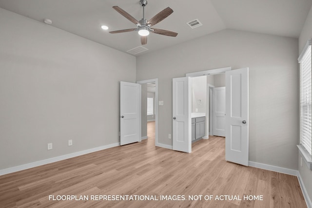 unfurnished bedroom with vaulted ceiling, multiple windows, connected bathroom, light wood-type flooring, and ceiling fan