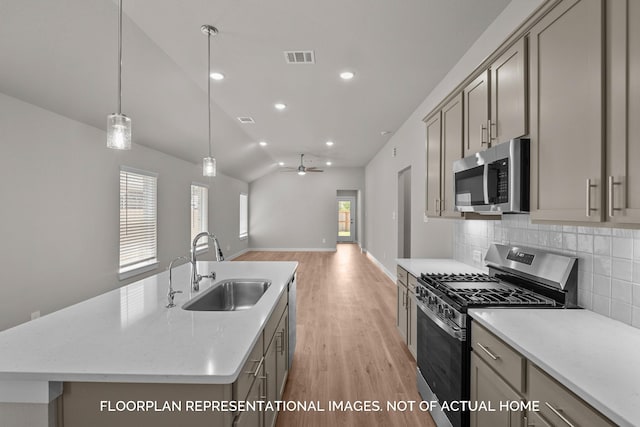 kitchen featuring ceiling fan, vaulted ceiling, sink, an island with sink, and stainless steel appliances