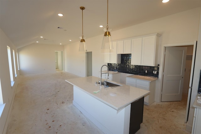 kitchen with decorative light fixtures, white cabinetry, sink, a kitchen island with sink, and light stone counters