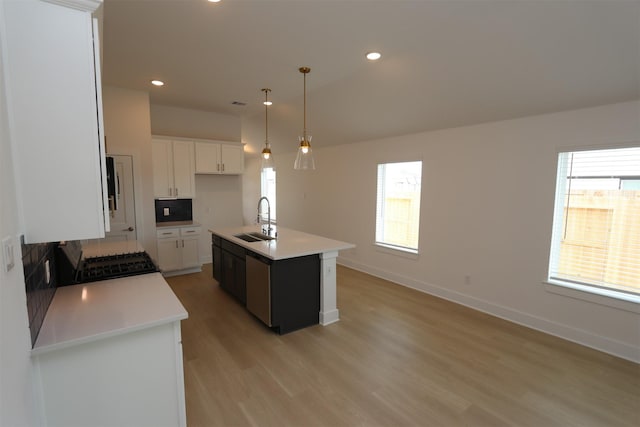 kitchen with white cabinetry, sink, decorative light fixtures, and an island with sink