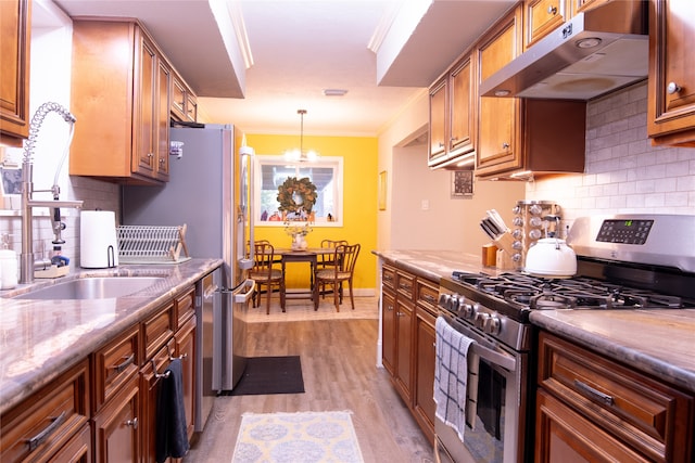 kitchen with light wood-type flooring, light stone counters, sink, stainless steel gas range oven, and ornamental molding