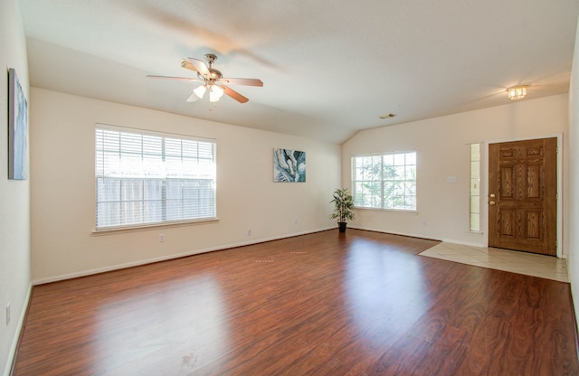 empty room with vaulted ceiling, plenty of natural light, and hardwood / wood-style floors