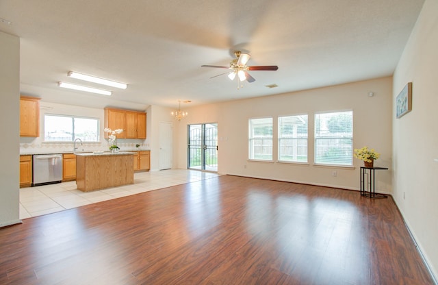 unfurnished living room with ceiling fan with notable chandelier, light wood-type flooring, and sink