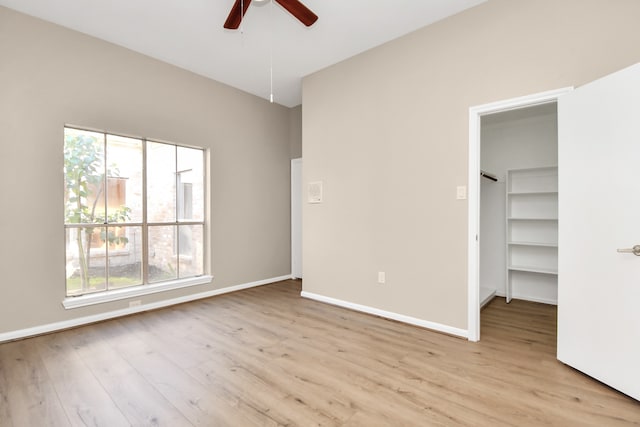 unfurnished bedroom featuring light hardwood / wood-style floors, ceiling fan, a spacious closet, and a closet