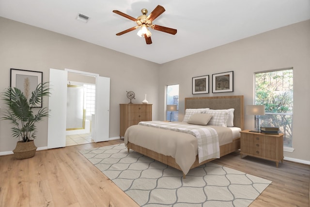 bedroom with ceiling fan, light hardwood / wood-style floors, and ensuite bath