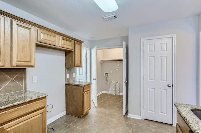 kitchen with decorative backsplash, light tile patterned floors, and light stone countertops