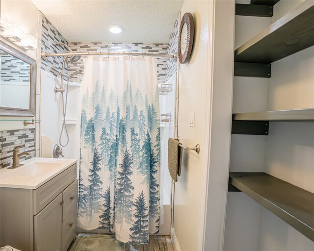 bathroom featuring walk in shower, decorative backsplash, a textured ceiling, and vanity