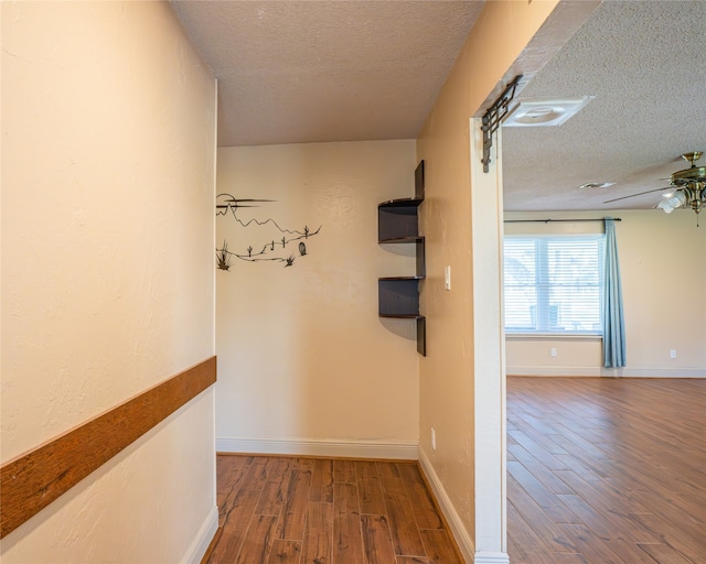 hallway with a textured ceiling and hardwood / wood-style flooring