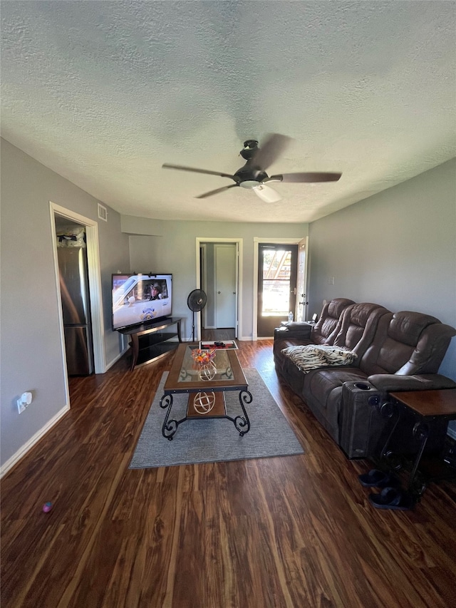 living room with a textured ceiling, ceiling fan, and dark hardwood / wood-style flooring