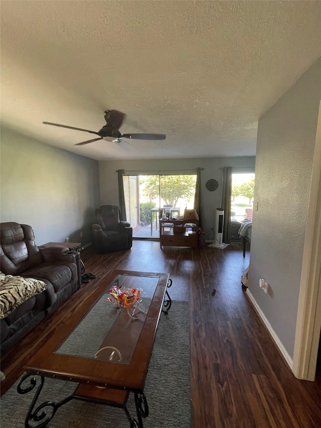 unfurnished living room featuring dark wood-type flooring, ceiling fan, a textured ceiling, and plenty of natural light