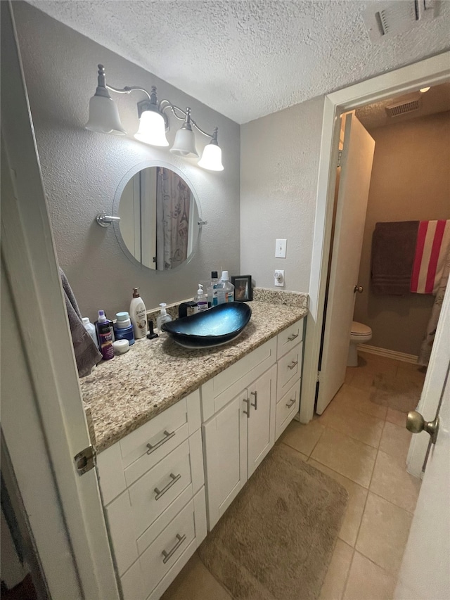 bathroom with vanity, toilet, tile patterned floors, and a textured ceiling