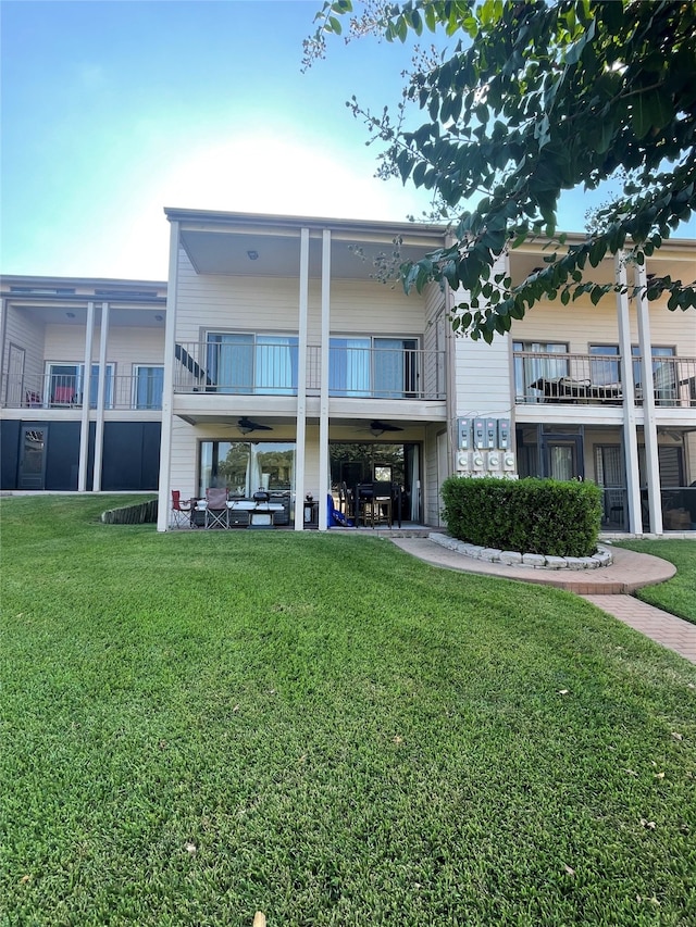 back of house featuring a balcony and a yard