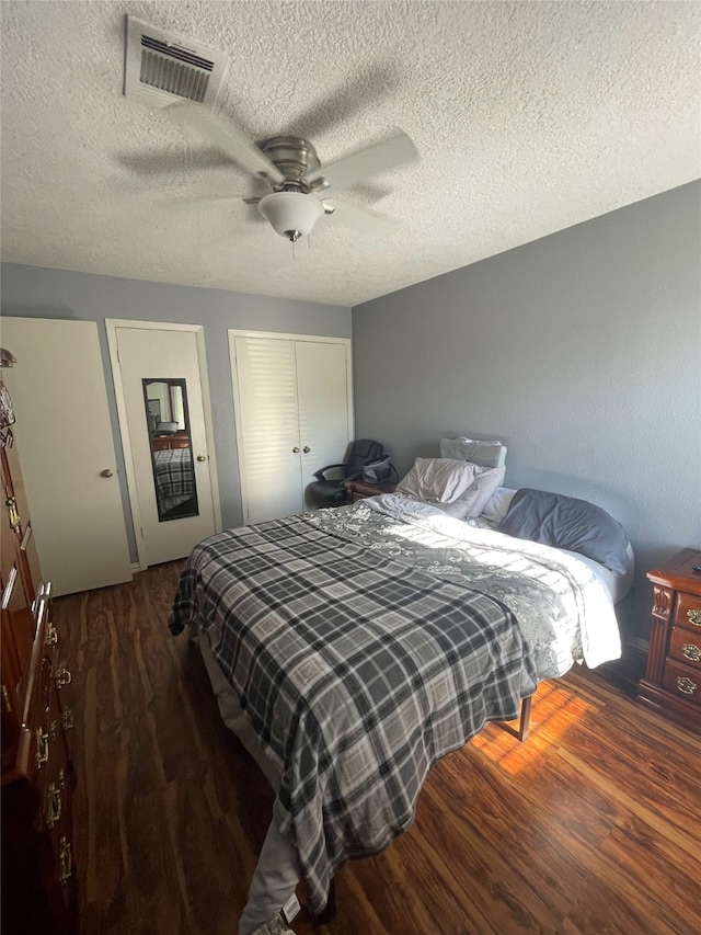 bedroom featuring dark hardwood / wood-style flooring, a textured ceiling, and ceiling fan