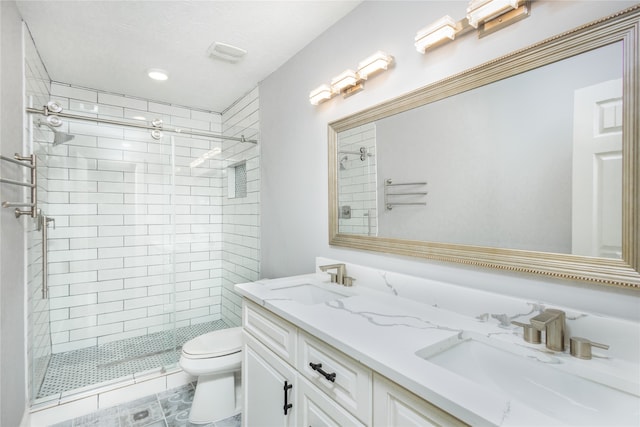 bathroom featuring toilet, a shower with shower door, vanity, and tile patterned floors