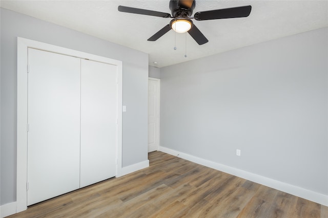 unfurnished bedroom with a closet, a textured ceiling, wood-type flooring, and ceiling fan