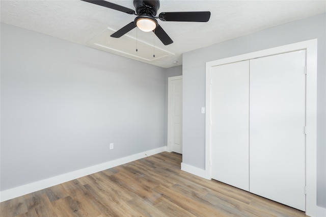 unfurnished bedroom featuring a textured ceiling, wood-type flooring, a closet, and ceiling fan