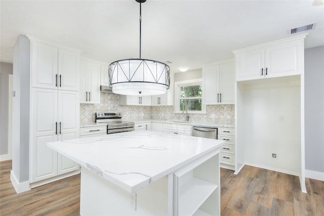 kitchen with a kitchen island, stainless steel appliances, pendant lighting, white cabinets, and hardwood / wood-style flooring