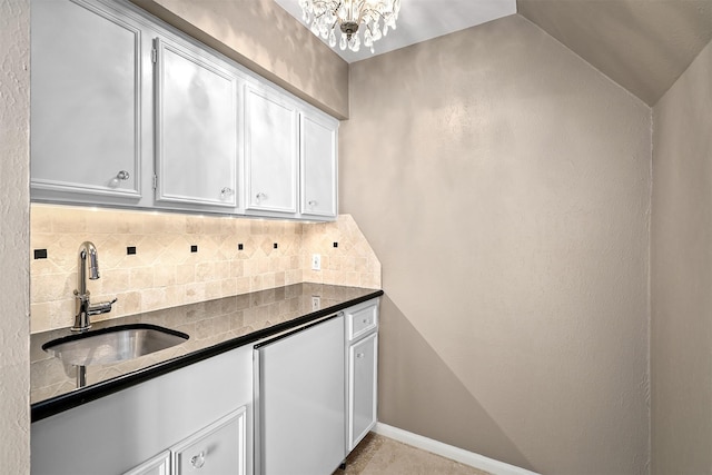 kitchen with lofted ceiling, sink, white cabinetry, an inviting chandelier, and tasteful backsplash