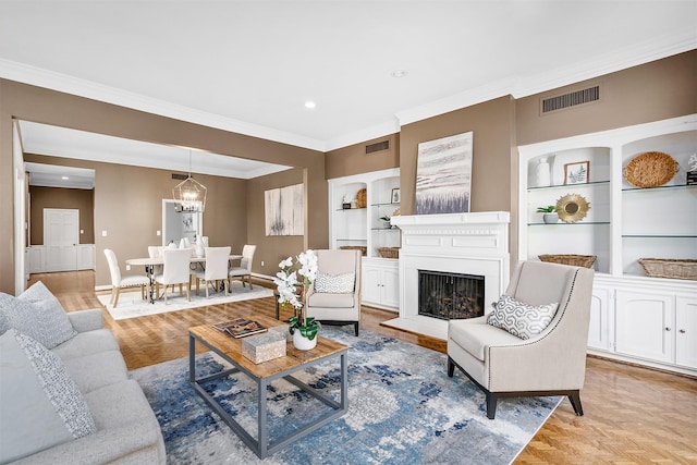 living room featuring built in shelves, ornamental molding, a chandelier, and light parquet flooring