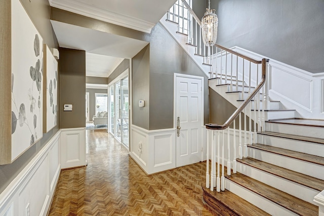 staircase with crown molding, parquet floors, and an inviting chandelier