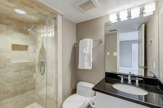 bathroom with vanity, a shower with door, and toilet