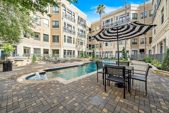 view of swimming pool with area for grilling, a patio area, and pool water feature