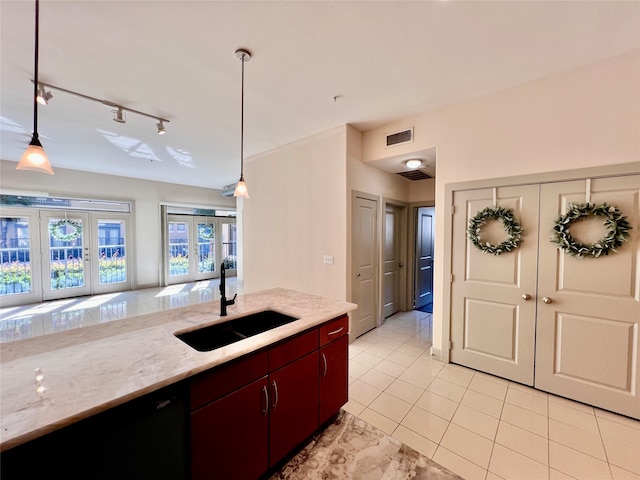 kitchen featuring hanging light fixtures, light stone counters, light tile patterned flooring, french doors, and sink