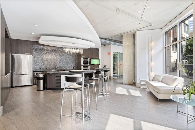 kitchen with appliances with stainless steel finishes, tasteful backsplash, dark brown cabinets, and light hardwood / wood-style floors