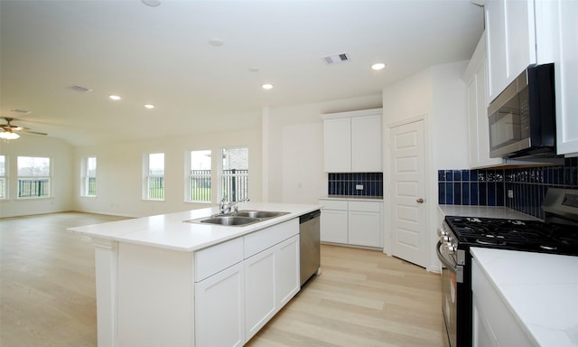 kitchen featuring white cabinets, stainless steel appliances, a kitchen island with sink, and sink