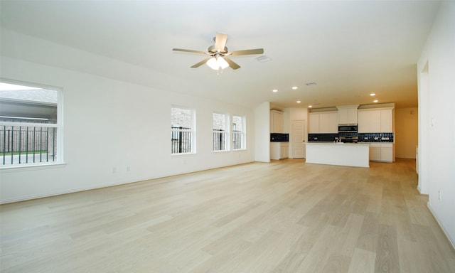 unfurnished living room featuring ceiling fan, a healthy amount of sunlight, and light hardwood / wood-style flooring