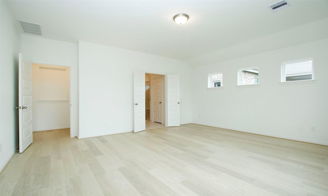 unfurnished bedroom with a walk in closet and light hardwood / wood-style flooring