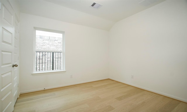 spare room featuring lofted ceiling and light wood-type flooring