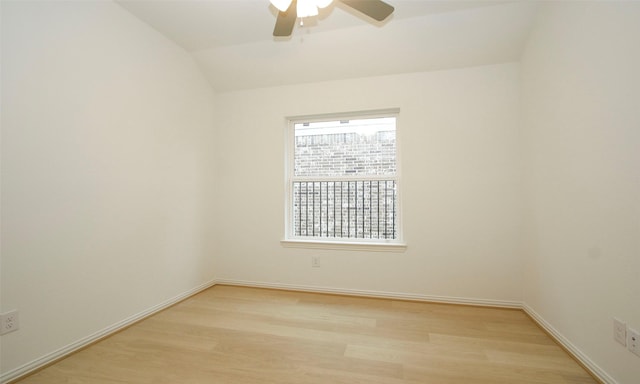 empty room featuring ceiling fan, plenty of natural light, vaulted ceiling, and light wood-type flooring