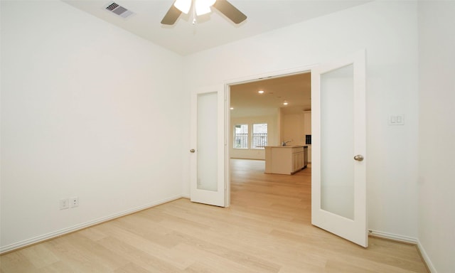 unfurnished room featuring french doors, light wood-type flooring, and ceiling fan