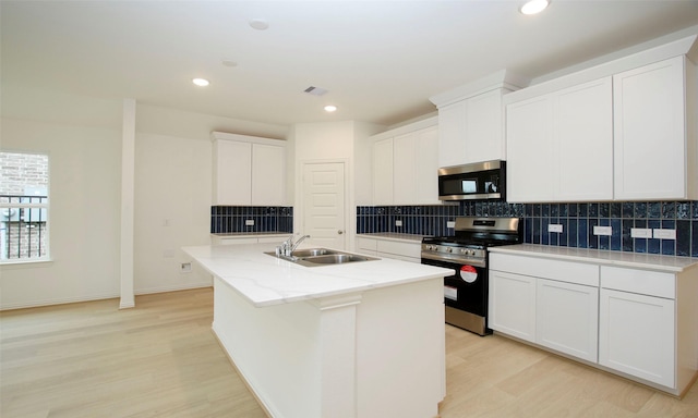 kitchen featuring sink, light hardwood / wood-style flooring, a center island with sink, white cabinets, and appliances with stainless steel finishes