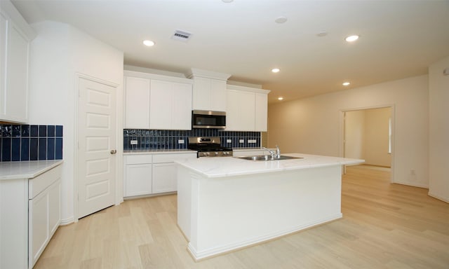 kitchen with white cabinets, stainless steel appliances, a kitchen island with sink, and sink