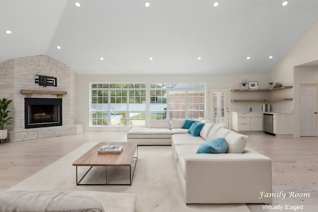 living room with light hardwood / wood-style floors, vaulted ceiling, a fireplace, and sink