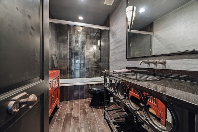 full bathroom with bath / shower combo with glass door, vanity, toilet, and hardwood / wood-style flooring