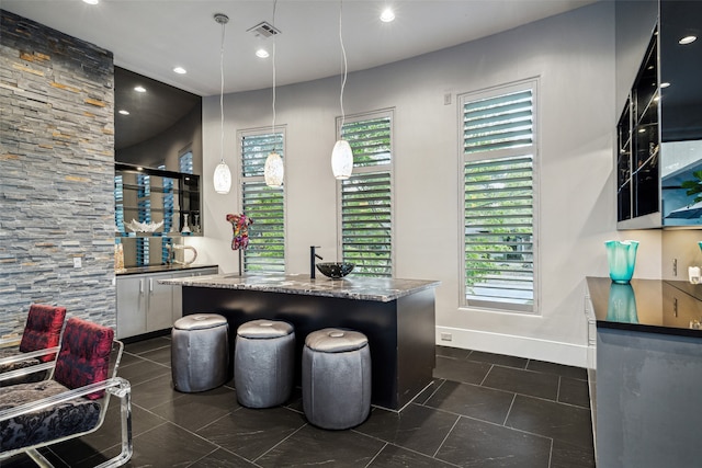 bar with dark stone counters and decorative light fixtures