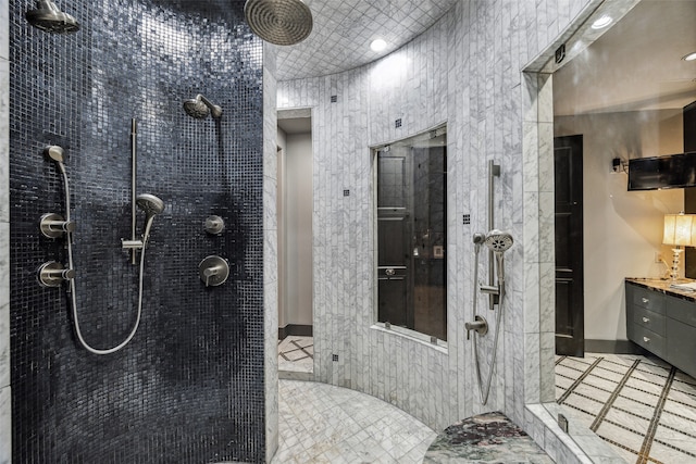 bathroom featuring vanity, tile walls, tile patterned flooring, and a tile shower