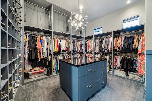 spacious closet with dark carpet and an inviting chandelier