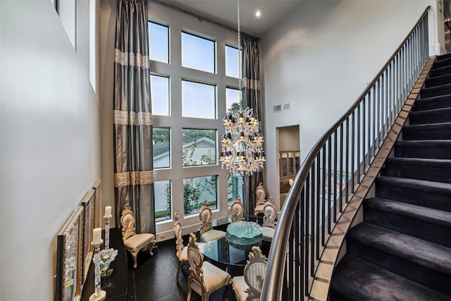 stairway featuring a notable chandelier, hardwood / wood-style flooring, a high ceiling, and a healthy amount of sunlight