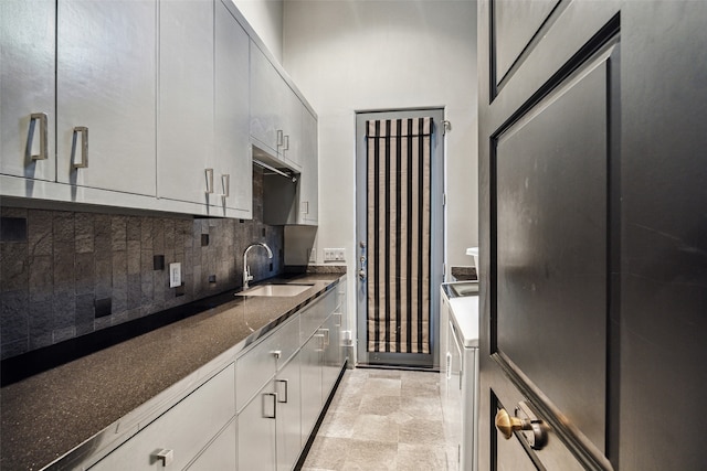 kitchen featuring decorative backsplash, dark stone countertops, sink, and washer / dryer