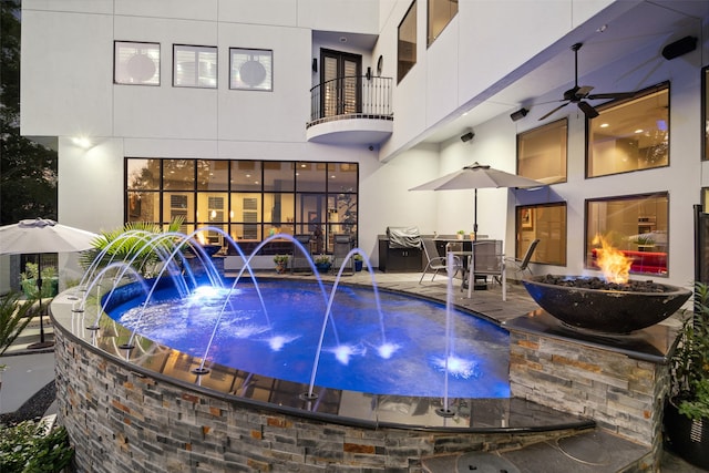 view of swimming pool with an outdoor fire pit, ceiling fan, pool water feature, and a patio